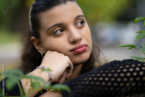 Bild auf Leinwand Thoughtful young woman daydreaming in a park