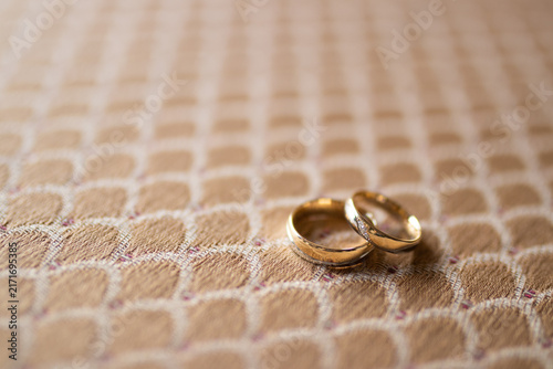Photography Two gold wedding rings sit on patterned fabric