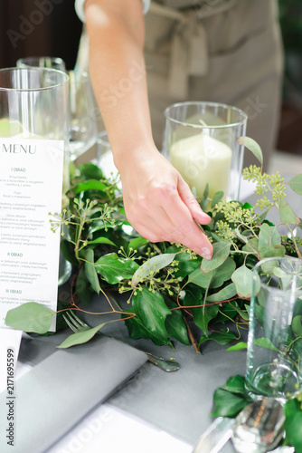 Woman arranging green garland on elegant dinner table