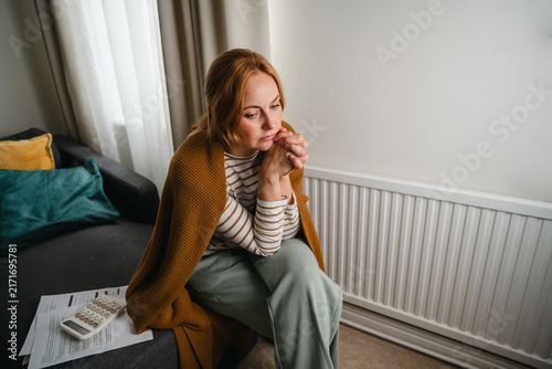 Stressed woman sits alone at home worrying about bills
