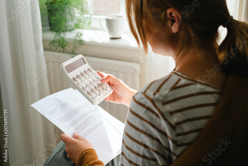 Woman reviewing bills with a calculator at home