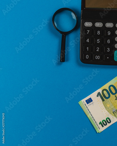 Tools for managing finances on a blue surface with cash and a calculator