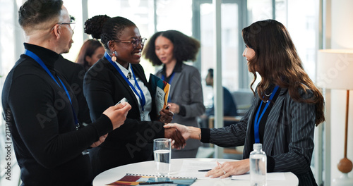 Business people  convention or shaking hands for greeting  meeting and introduction with smile. Seminar  happy group or handshake for welcome  partnership collaboration or workshop event with paper