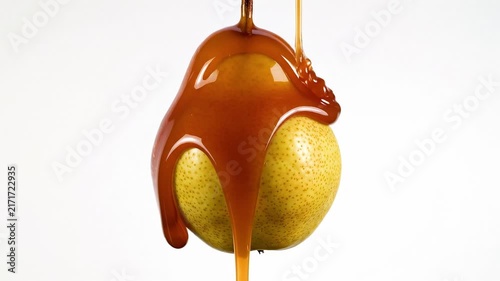 Sweet Caramel Sauce Drizzling Over Fresh Ripe Pear Isolated on White Background.