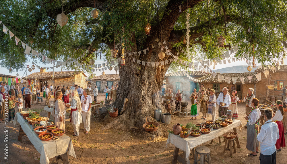 Obraz premium People gathered around a large tree at an outdoor festival or market.