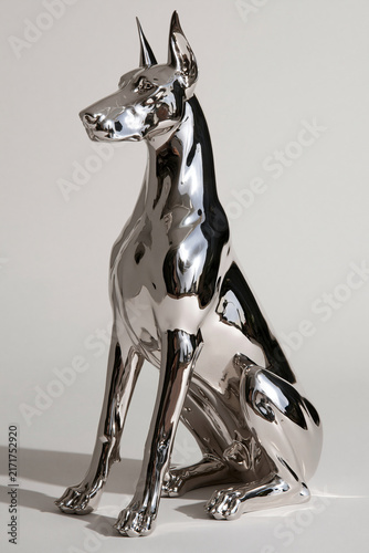 a super glossy sculpture of a seated dobermann dog with a chrome finish