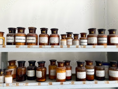 vintage amber chemical bottles arranged on wooden pharmacy shelves, jars of medicines
