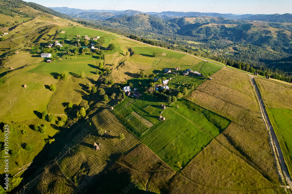 Naklejka premium Aerial view of picturesque rural landscape at sunrise, with rolling hills and lush green fields.