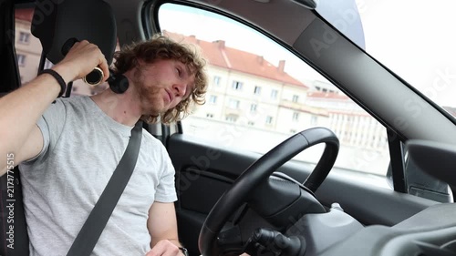 Driver massages his aching neck with a massage gun after long hours on the road relieving soreness and muscle tension caused by extended driving while resting inside his car