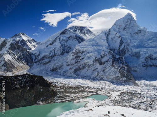 Photography Panoramic view of Mount Everest and surrounding Himalayan peaks with a glacial lake and icefall under a clear blue sky in Nepal