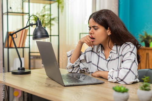 Foto Indian woman at home watches laptop screen pressing lips feeling sad about touching story sensing pain