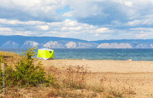 Baikal Lake in summer. A camping green tent on the sandy beach of the Small Sea. Outdoor recreation