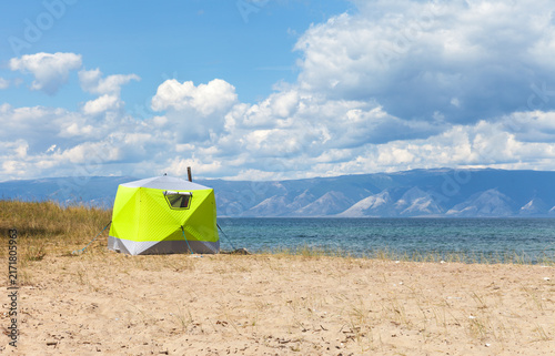 Lake Baikal in summer. Olkhon Island. A green camping tent on a sandy beach in a warm bay of the Small Sea on a sunny August day. Summer travel and outdoor recreation