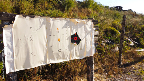 Принти на полотні Paper Target Board with Bullet Holes at Outdoor Shooting Range