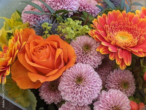 Vibrant autumn bouquet with orange gerbera daisy, pink chrysanthemums, orange rose and red hypericum berries close up