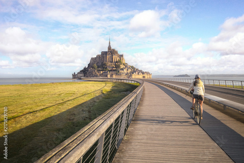 femme à vélo, arrivant devant le Mont Saint Michel en Normandie