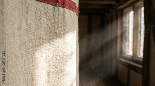Sunlit coarse canvas cloth with red trim in dusty interior