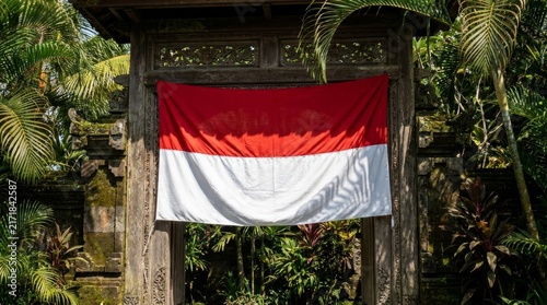 Wide Indonesian flag draped across ornate wooden temple portal
