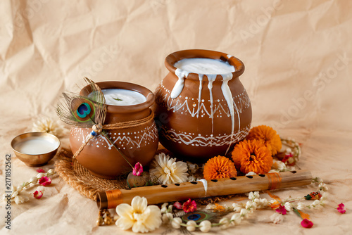Traditional Janmashtami Still Life Setup Featuring Clay Pots Filled With Cream Peacock Feather Bamboo Flute Garland Of Fresh Marigold Flowers