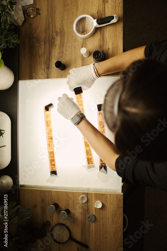 Foto High angle view of young Caucasian woman wearing gloves and examining analog fil