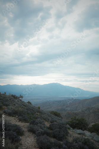 Desert valley overlook with layered mountain ridges beneath a cloudy sky in Joshua Tree National Park, California