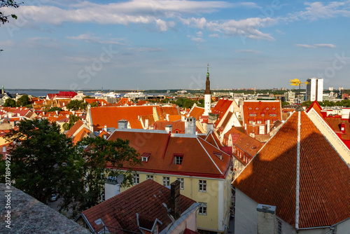 Foto Panoramic cityscape view of the historic Old Town of Tallinn, Estonia, with countless terracotta-tiled roofs and church spires illuminated by warm evening light
