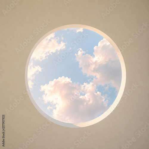 Circular skylight with blue sky and soft white clouds viewed from below