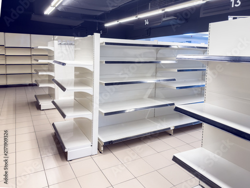 Empty supermarket shelving illustrating food shortage and economic crisis concept