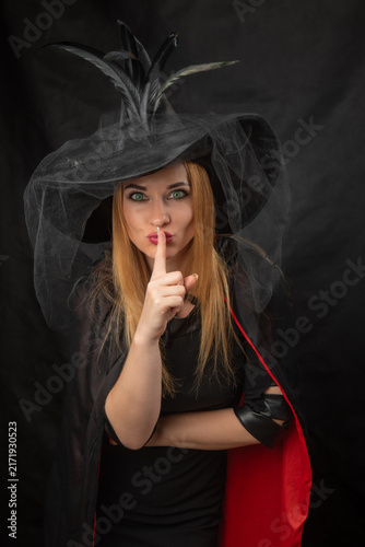 Foto Woman dressed in a witch costume with a black feathered hat and a red lined cape