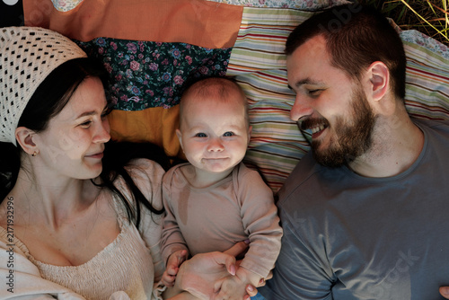 Картината върху платно Happy family enjoying a picnic outdoors with their baby on a colorful blanket