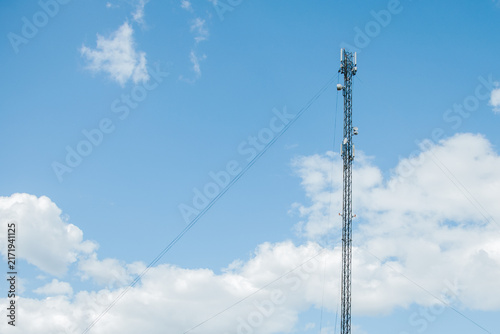 Fotografía A tall telecommunications mast equipped with several panel antennas, microwave dishes, cables and radio equipment against a clear, blue sky