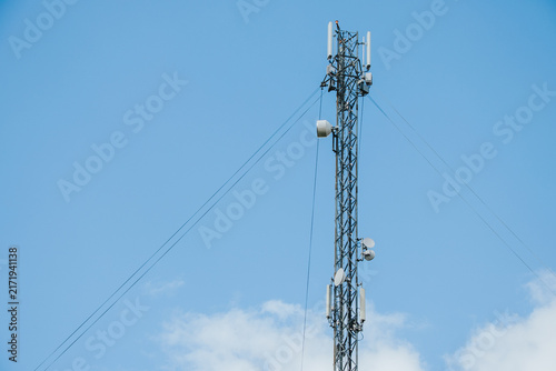 Quadro su tela A tall telecommunications mast equipped with several panel antennas, microwave dishes, cables and radio equipment against a clear, blue sky