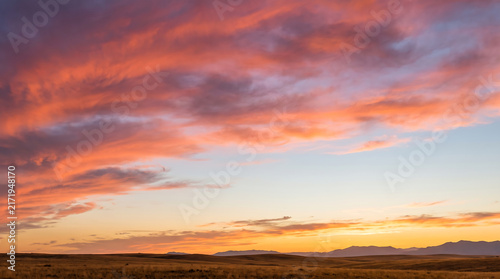 Vibrant pink and orange clouds light up the sunset sky over a peaceful prairie landscape