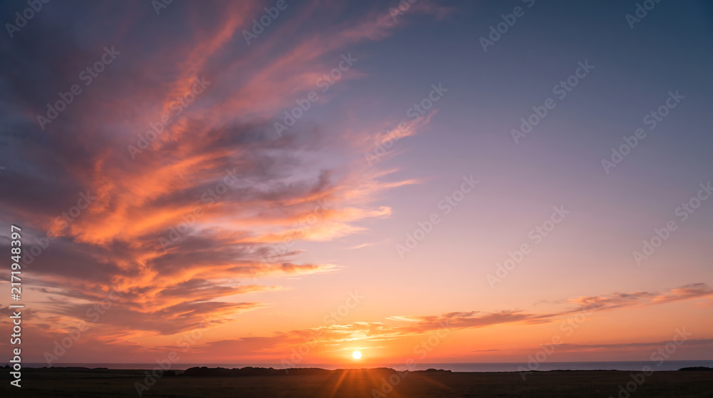 Fototapeta premium Vibrant Sunset Sky with Radiant Orange and Pink Clouds over Horizon Landscape