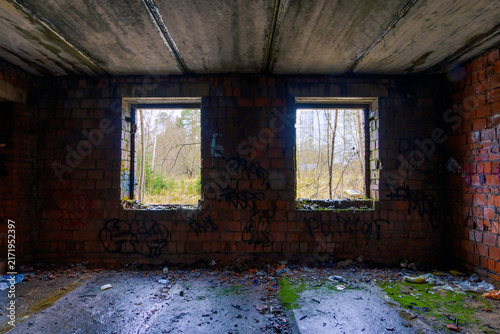 Quadro su tela Dim empty room inside abandoned brick building with two square window openings f