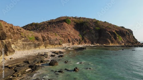 Aerial drone flying over low tide reef flat toward backlit coastline at golden hour Lombok Indonesia