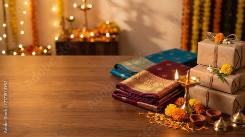 Elegant Festive Setup Featuring Traditional Silk Sarees and Golden Oil Lamps for Diwali Celebration with Decorated Gift Boxes on Wooden Table Surface