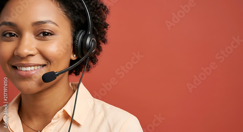 Friendly Black female customer support woman wearing headset against red copy space background. Close-up shot of a smiling call center operator providing professional client assistance.