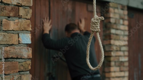 A nervous man on the background of a rope with a noose for suicide. A man on the verge of death. Suicide by hanging. Human psychology. Nervous breakdown.