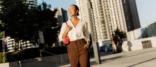 Cuadro en lienzo Korean woman walking confidently in a vibrant cityscape as the sun shines