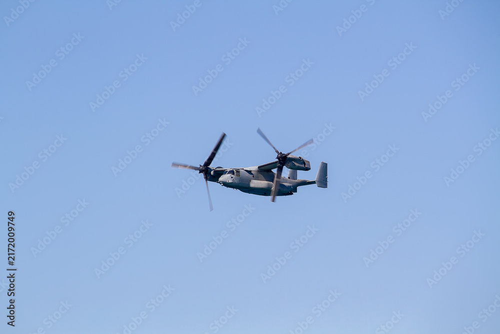 Fototapeta premium V-22 Osprey military tiltrotor aircraft flying against a clear blue sky, photographed in side profile with its distinctive twin rotors, engines, wings and rear fuselage clearly visible.