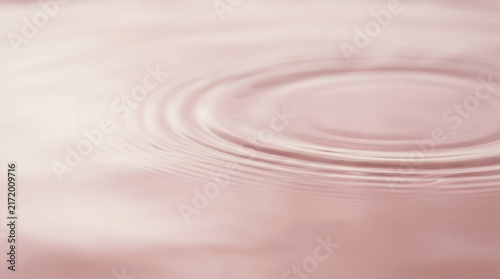 Gentle ripples on a calm pink water surface creating a peaceful abstract background