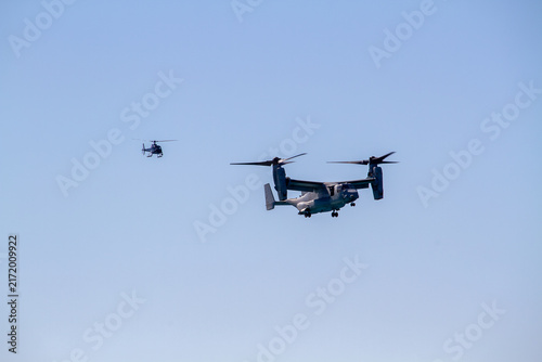 Fotografía V-22 Osprey military tiltrotor aircraft flying against a clear blue sky, photographed in side profile with its distinctive twin rotors, engines, wings and rear fuselage clearly visible