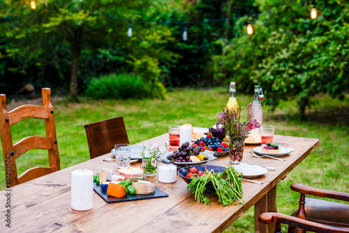Bild auf Leinwand Outdoor table with fruits, cheese, and drinks set for a gathering
