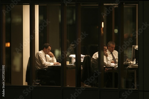 Business people working late at night in a modern office building viewed from the outside