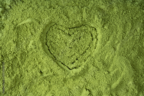 Close-up of a heart shape drawn in vibrant green matcha powder.