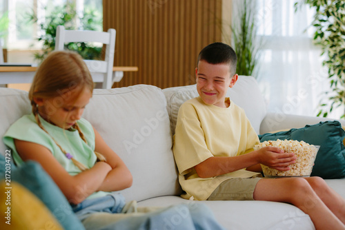 Canvas Print Two siblings on a sofa in the living room during a petty argument: boy teasing w