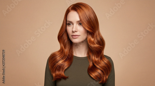 Beautiful Woman with Vibrant Copper Red Wavy Hair Portrayed on Studio Background