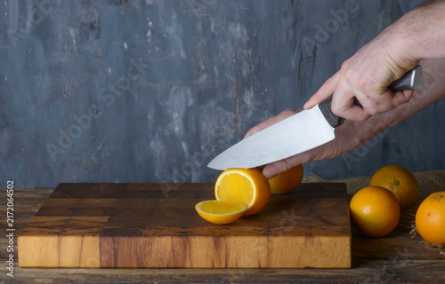 Chef Slicing Fresh Oranges on Wooden Board