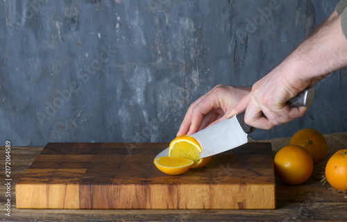 Chef Slicing Fresh Oranges on Wooden Board